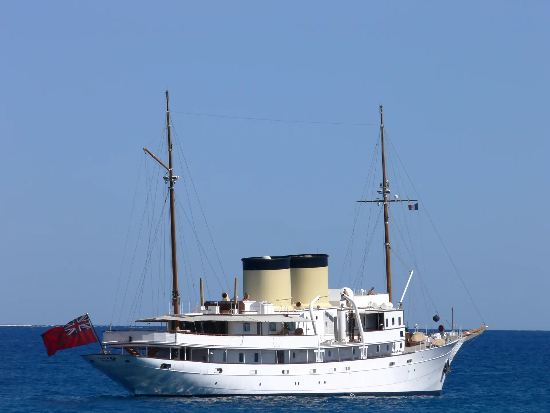 Bow-quarter view of Talitha at anchor with red ensign