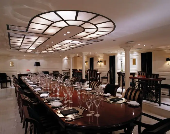 Formal dining room with a long table, upholstered chairs and panelled walls