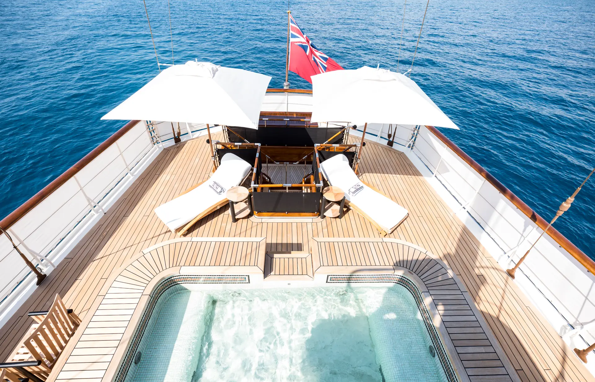 Aft deck pool with teak decking, parasols and sun loungers