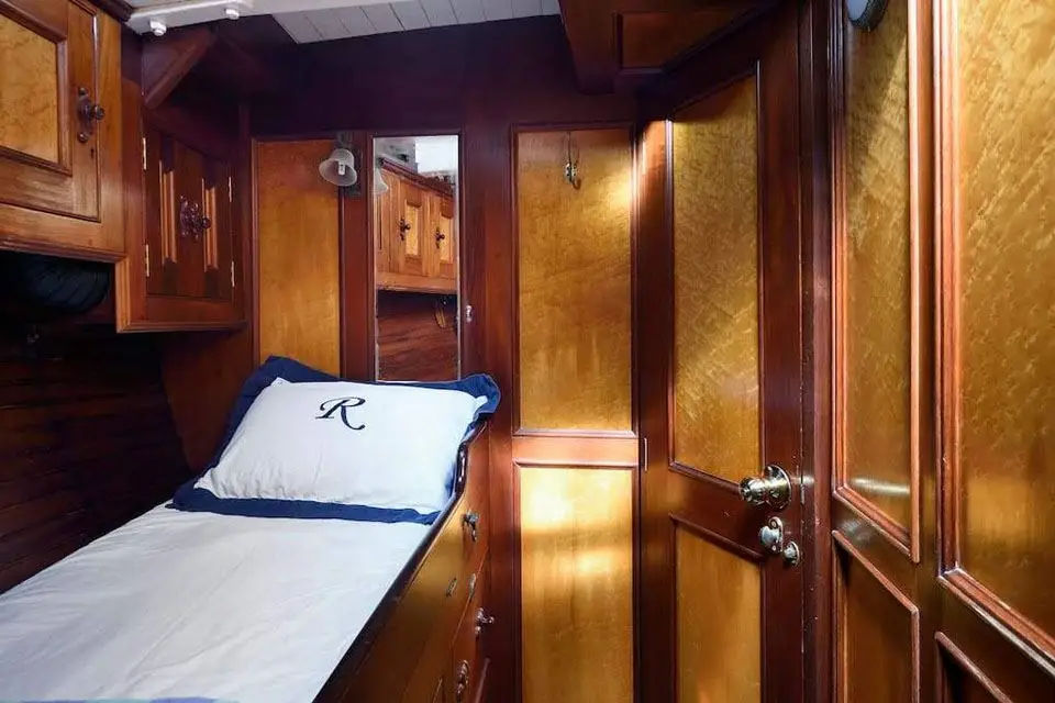 Single-berth cabin with monogrammed pillow, mirror and burr-panelled locker doors
