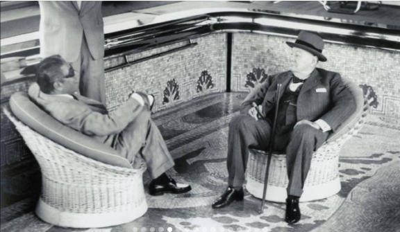 Two men seated in wicker chairs beside the mosaic pool aboard the yacht Christina