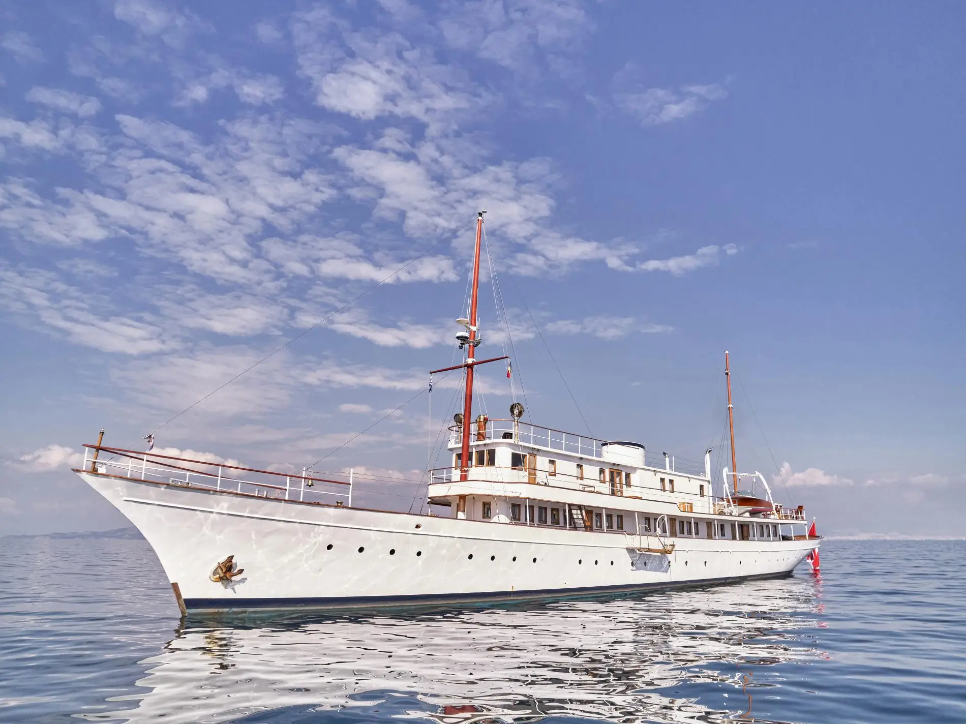 Madiz lying still, bow towards the camera, with varnished masts and white superstructure
