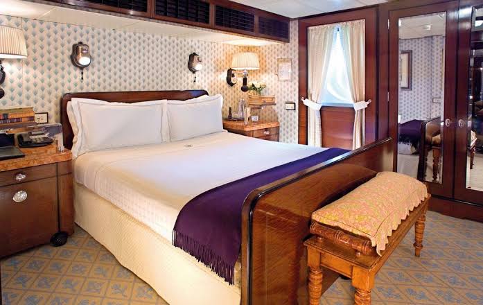 Double cabin with a burr-veneered bedstead, wall lights and mirrored wardrobe