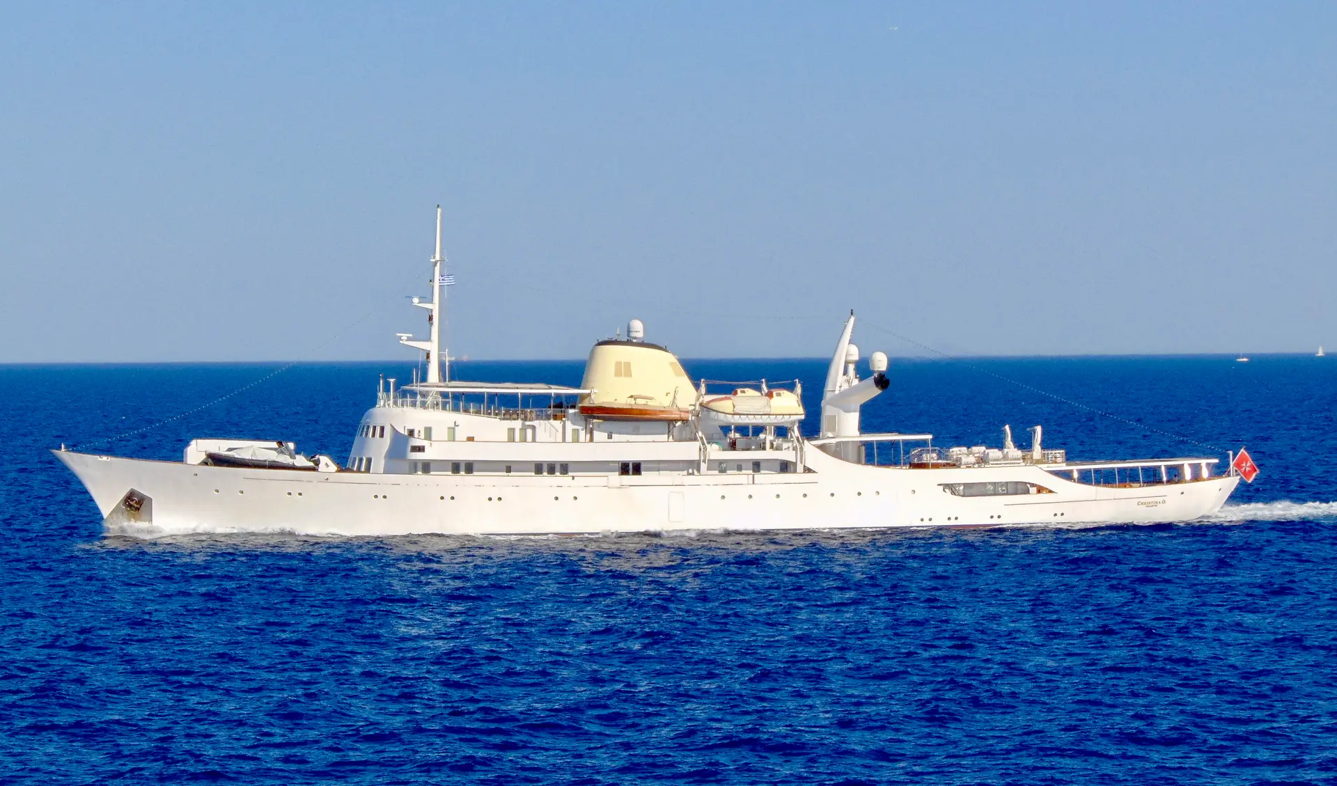 Christina O under way at sea, bow wave breaking along her white hull