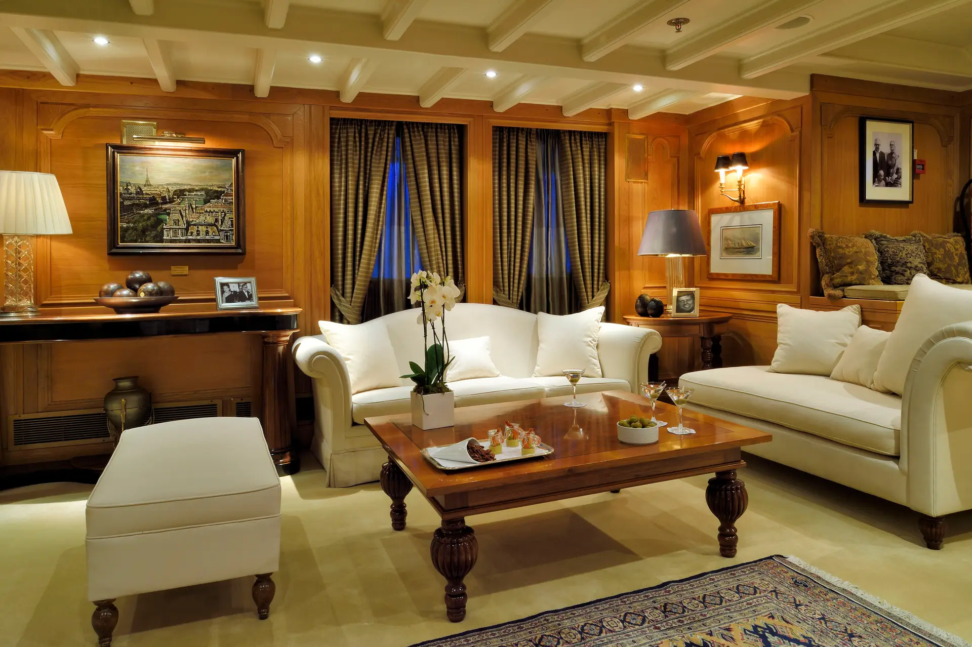Panelled main salon with seating groups, patterned rugs and large windows