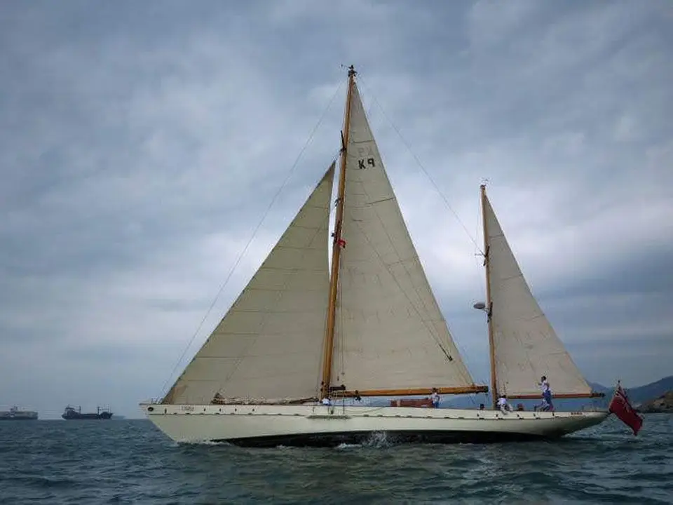 Rona under full sail on a grey sea, sail number K9