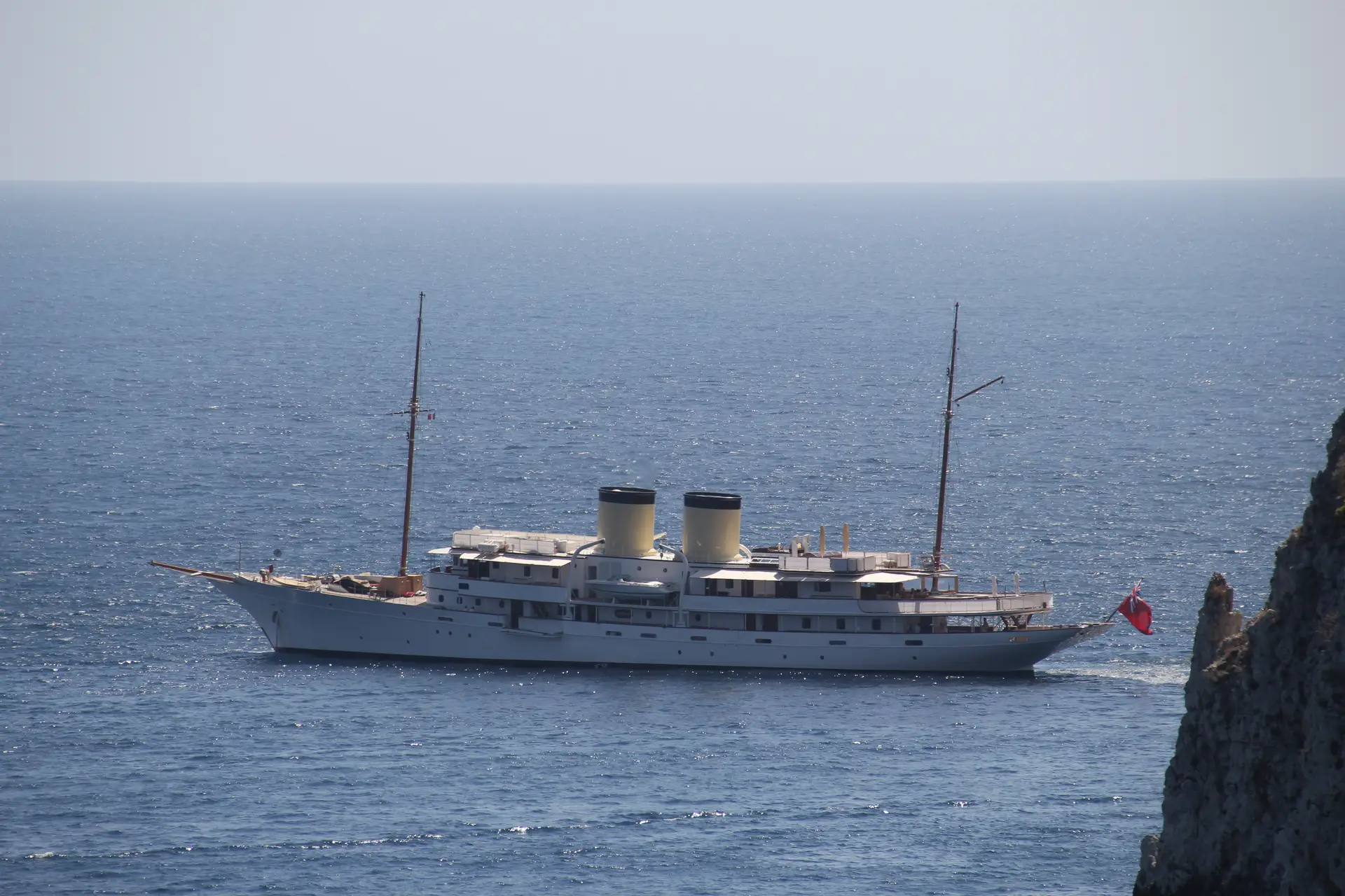 Talitha at anchor off a rocky coastline seen from above