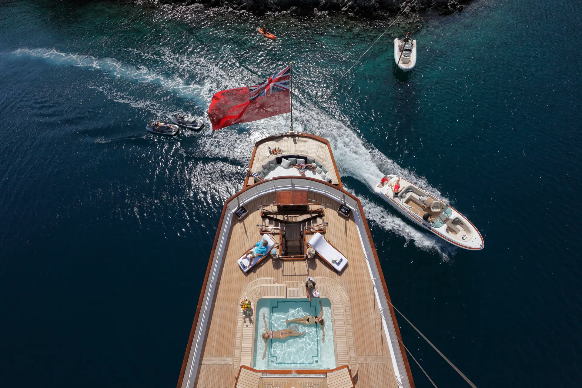 Aerial view down Talitha's aft deck showing the pool, sun loungers and tenders under way