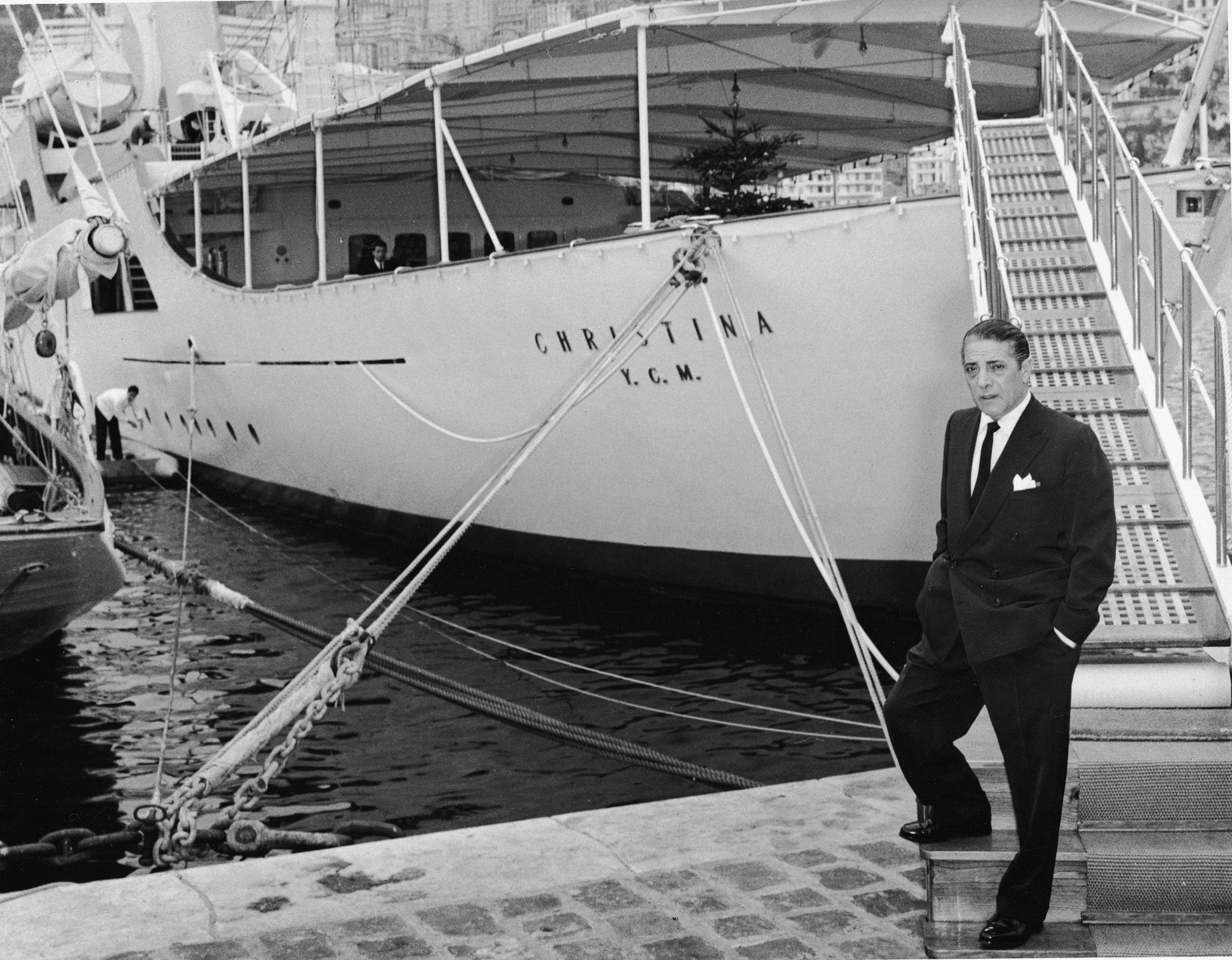 Aristotle Onassis standing at the gangway of the yacht Christina in a harbour